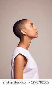 Side View Of A Female In Casuals With Shaved Head. Androgynous Woman Looking Up On Colored Background.