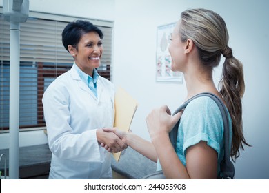 Side View Of Female Dentist Shaking Hands With Woman