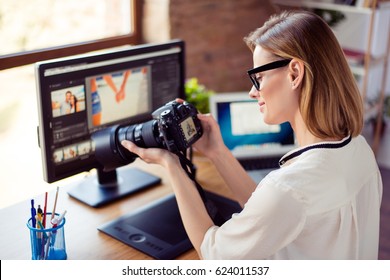 Side view  of female freelancer photographer cheking  photos on a digital camera while sitting at the table in workstation - Shutterstock ID 624011537