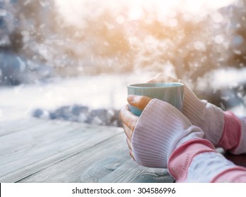 Side view of female hand holding hot cup of coffee in winter - Photo in vintage color image style.