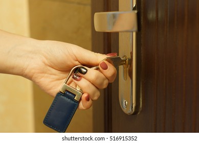 Side View Female Hand Holding Key To Insert In Door Lock