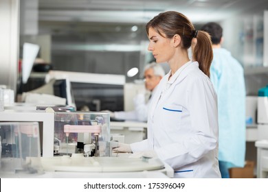 Side View Of Female Researcher Using Centrifuge In Medical Lab