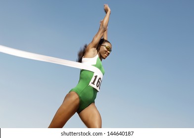 Side View Of A Female Runner Winning Race Against The Blue Sky