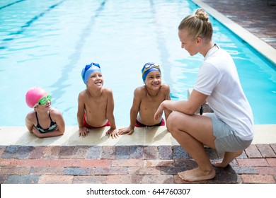 Side view of female swimming trainer teaching students at pool side - Powered by Shutterstock