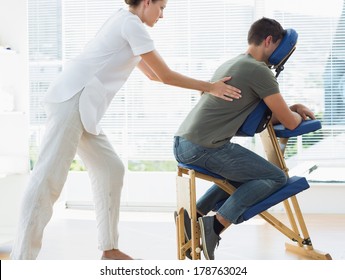 Side view of female therapist massaging man in hospital