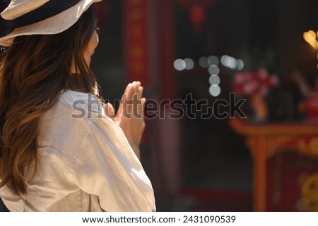 Side view of female tourist praying at a shrine at Chinese temple for blessing, grace and gratitude