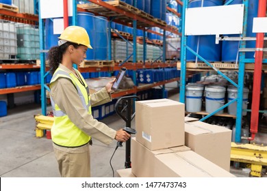 Side View Of Female Worker Scanning Package With Barcode Scanner While Using Digital Tablet In Warehouse. This Is A Freight Transportation And Distribution Warehouse. Industrial And Industrial Workers