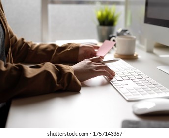 Side view of female working with computer device while looking an idea on notepad on white office desk 