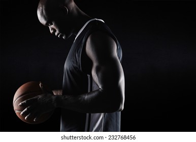 Side view of fit young basketball player holding ball against black background with copy space. African american basketball player with ball. - Powered by Shutterstock