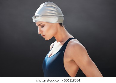 Side View Of Fit Young Female Swimmer On Black Background. Fitness Woman In Swimming Costume Concentrating.