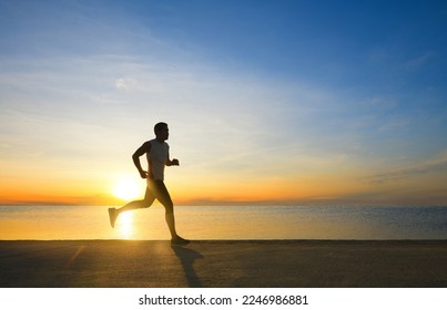 Side view of fitness man jogging on the seaside concrete road with sunrise background. - Powered by Shutterstock