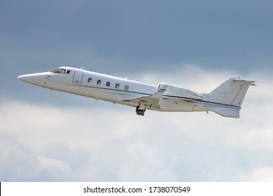 Side View Of Flying Small Turbofan-powered Business Jet Airplane After Taking Off. White Commercial Passenger Jet In Flight, No Painting. Modern Technology In Fast Transportation. Aviation And Travel.