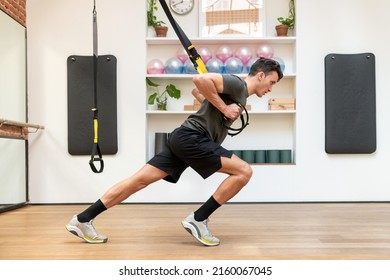 Side View Of Focused Athletic Man In Sportswear Doing Exercises On TRX Ropes During Suspension Training In Spacious Fitness Club