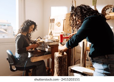 Side view of focused female jewellers in casual clothes making metallic accessories in workshop while working on project in daylight - Powered by Shutterstock