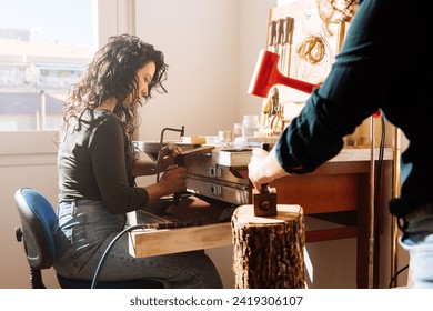 Side view of focused female jewellers in casual clothes making metallic accessories in workshop using hacksaw and hammer - Powered by Shutterstock