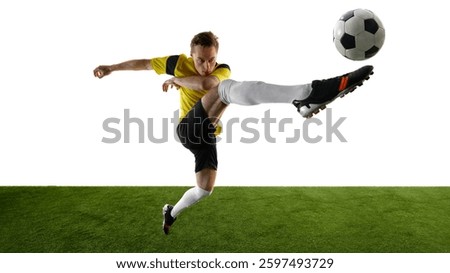 Side view of focused young man, soccer player performing acrobatic high kick, lifting leg towards ball, focusing intensely against white background. Concept of dynamic movement, competition, training.