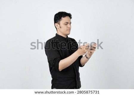 Side view of focused young man looking at smartphone with serious expression against white background