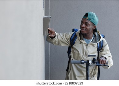 Side View Of Food Delivery Boy Ringing Doorbell While Riding Electric Scooter