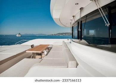 Side view of the forward deck of a superyacht, with bridge windows and seating lounge area with sea view - Powered by Shutterstock