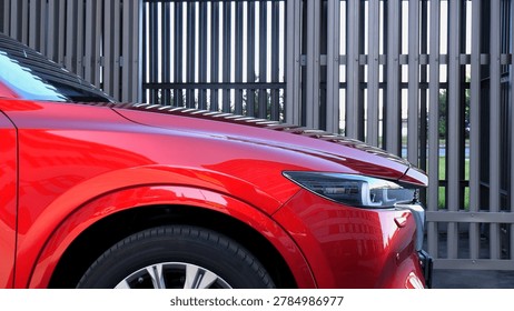 Side view of the front headlight and hood of the original red sports SUV against the background of steel stripes
