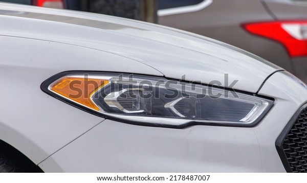 Side view of the front of a\
white car with headlights. A modern and elegant white car is a\
close-up of a car headlight with a copy space. White car\
headlight.