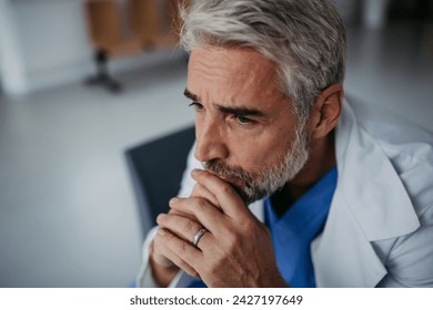 Side view of frustrated, exhausted doctor sitting in hospital corridor. Concept of burnout syndrome among doctors. - Powered by Shutterstock - Get 15% off with code: PIKWIZARD15