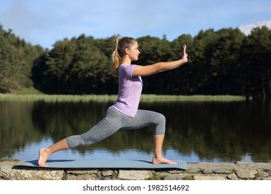 Side view full body portrait of a woman practicing tai chi pose in a lake