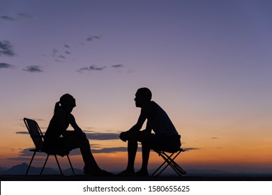 Side View Of A Full Body Of Two Friends Or Couple Silhouette Of Teens Sitting And Talking At Sunrise On The Beach