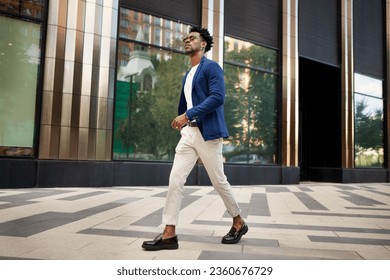 Side view full length man walks outside and wears trendy business clothes, blue jacket, white pants and loafer shoes. Stylish fashion male model, Street style. - Powered by Shutterstock