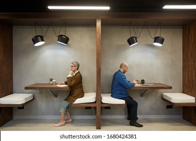 Side View Full Length Portrait Of Two Adult People Separated By Wall While Sitting In Separate Cafe Booths, Copy Space