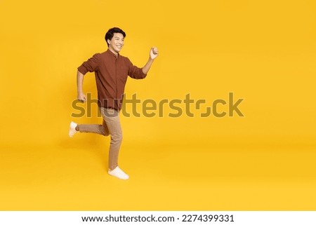 Side view of full length portrait of Asian young businessman walking isolated on yellow background