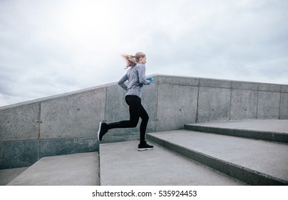 Side View Full Length Shot Of Fit Young Woman Running Up Stairs. Fitness Female On Morning Workout.