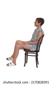 Side  View Of A Full Portrait Of A Middle Aged Woman Sitting On Chair Legs Crossed On White Background