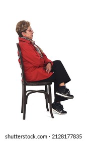 Side View Of A Full Portrait Of Serious Senior Woman With Shirt And Pants Sitting On Chair On White Background