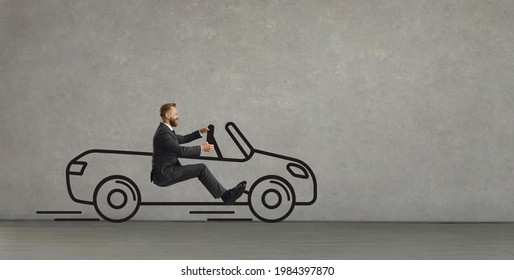 Side View Of Funny Excited Young Man Driving Imaginary Car Of His Dream. Happy Confident Businessman In Office Suit Sitting In Hand Drawn Automobile Going Straight Ahead On Grey Copy Space Background