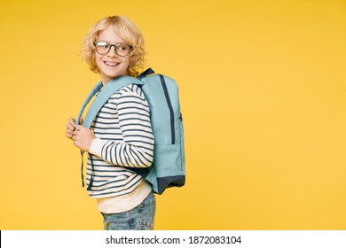 Side view of funny little male kid teen boy 10s years old in casual striped sweatshirt eyeglasses backpack looking aside isolated on yellow color background, child studio portrait. Education concept - Powered by Shutterstock