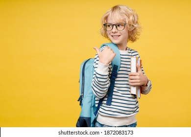 Side view of funny male kid teen boy 10s years old in striped sweatshirt glasses backpack hold school books pointing thumb aside isolated on yellow background child studio portrait. Education concept - Powered by Shutterstock