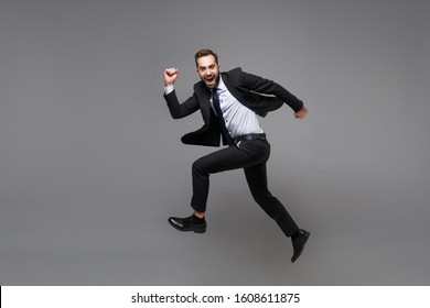 Side View Of Funny Young Business Man In Classic Suit Shirt Tie Posing Isolated On Grey Background. Achievement Career Wealth Business Concept. Mock Up Copy Space. Jumping, Running, Fooling Around