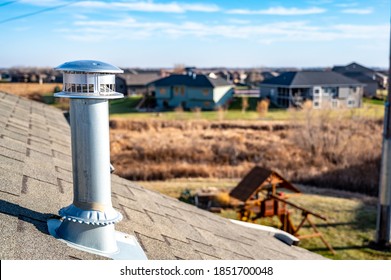 side view of a Galvanized metal chimney exhaust on  asphalt roof with a rain cap