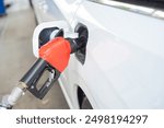 Side view gas pump nozzle inserts into capless fuel filler refueling for modern large SUV minivan car with slide door at gas station in San Antonio, Texas, oil and gas, transportation background. USA