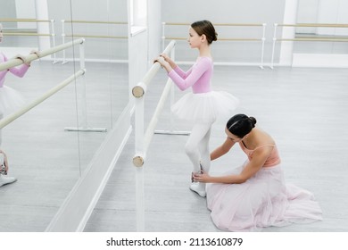 Side View Of Girl Training In Ballet School Near Mirrors And Dance Teacher