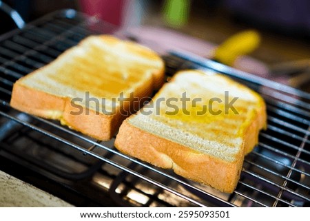Side view of group of buttered bread slices placed on a toaster until golden brown for a breakfast appetizer, vegan food.
