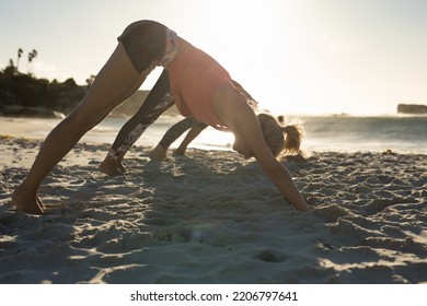 Side View Of A Group Of Caucasian Female Friends Enjoying Free Time On A Beach On A Sunny Day, Practicing Yoga