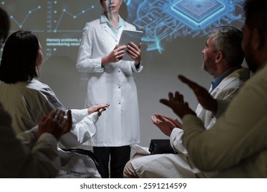 Side view of group of unrecognizable doctors sitting in row in audience at medical conference and applauding to speaker, copy space
