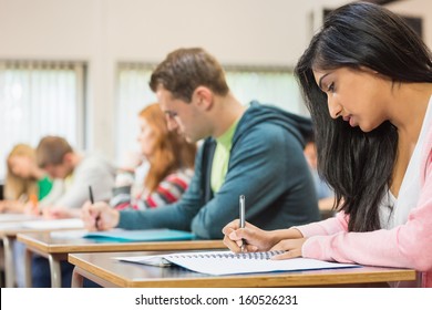 Side View Of A Group Of Young Students Writing Notes In The Classroom