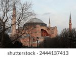 Side view of Hagia Sofia with the tree trunks in the foreground. 