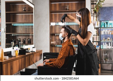 Side View Of Hairstylist In Face Shield And Latex Gloves Cutting Hair Of Client In Medical Mask