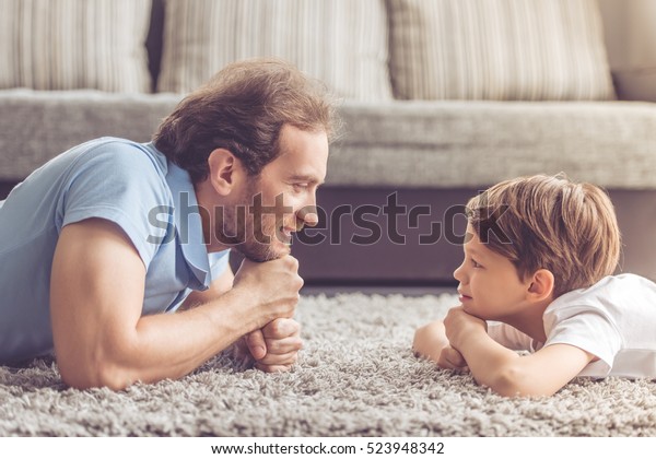 ハンサムな父親とかわいい息子がお互いを見つめ合い 家で過ごしながらにこにこ笑っている様子 の写真素材 今すぐ編集