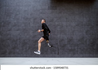 Side View Of Handsome Fit Caucasian Sportsman With Artificial Leg Running Outside.