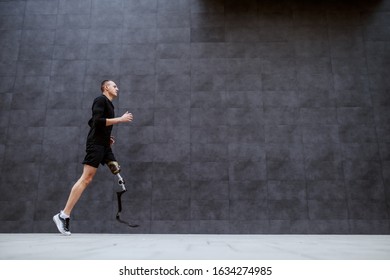 Side View Of Handsome Fit Caucasian Sportsman With Artificial Leg Running Outside.